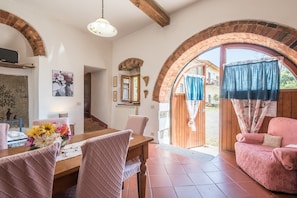 Un'area pranzo con un tavolo in legno, sedie rosa e un centrotavola floreale.
