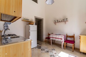A compact kitchen with a sink, stove, refrigerator, and a dining area with a table and chairs.