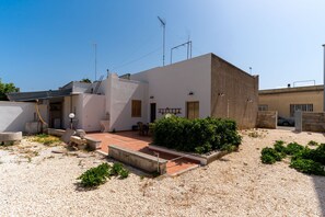 A residential building with a patio area, outdoor seating, and a small garden.