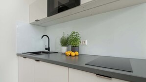 Een moderne keuken met een zwarte kraan, een magnetron boven het aanrecht en een potplant met citroenen op het aanrecht.