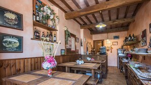 Ein rustikales Restaurant mit Holztischen, Bänken und einer Auswahl an Flaschen auf Regalen.