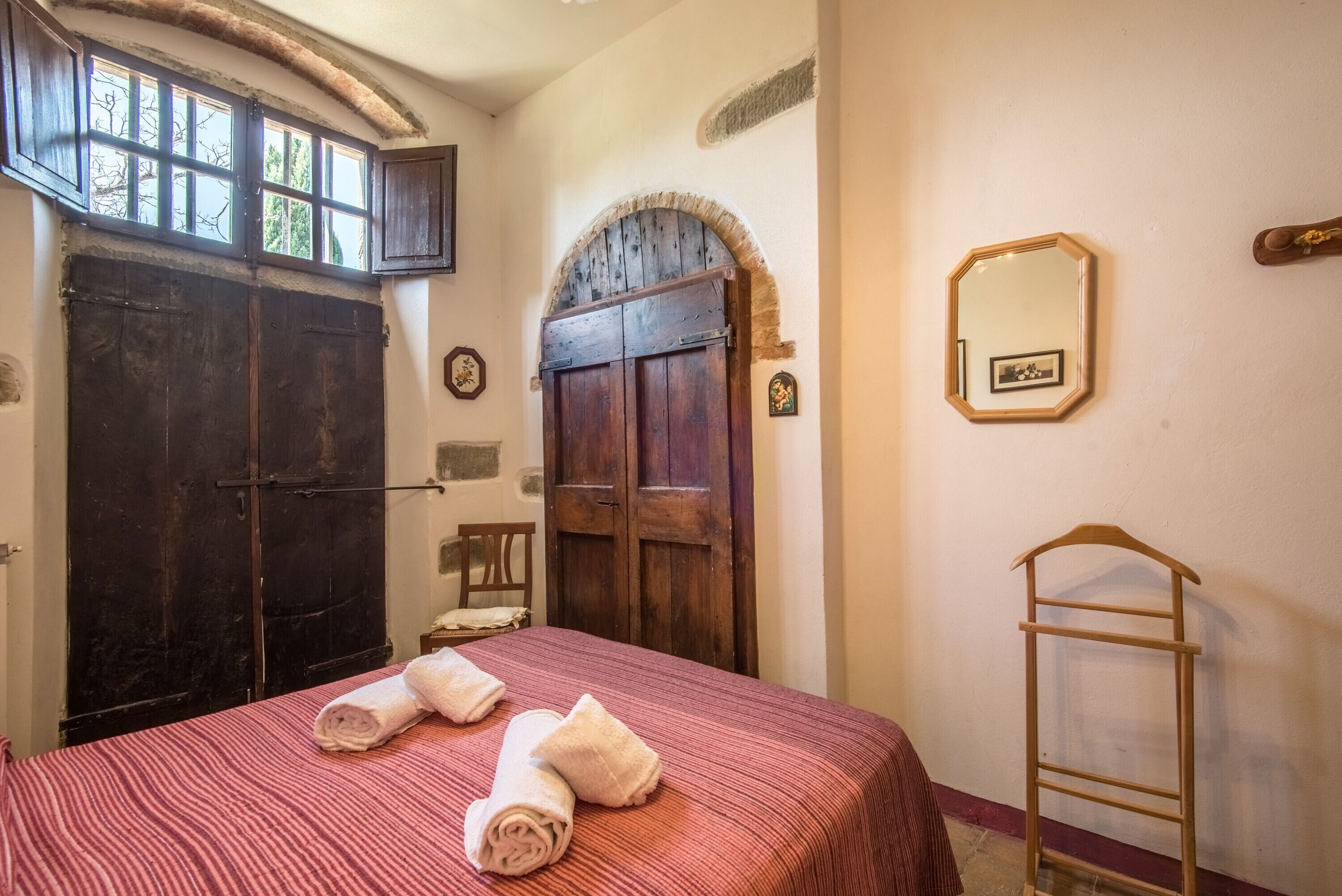 Een kamer met een bed, twee deuren, een spiegel en een houten trap.