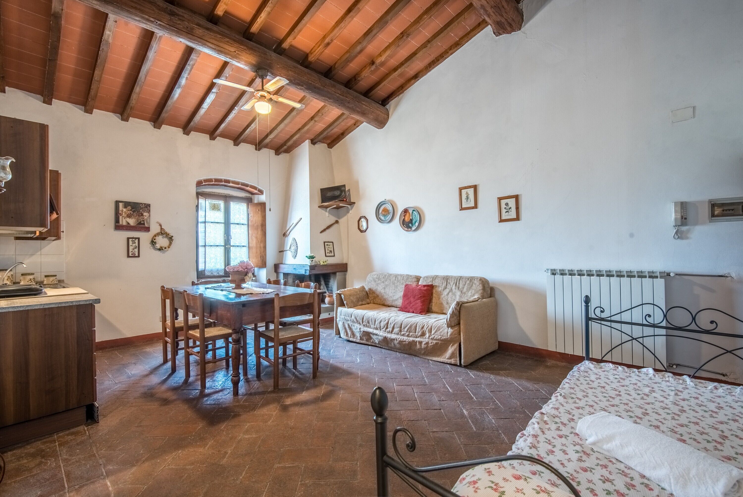 A cozy room with a dining table, chairs, a sofa, a bed, and a ceiling fan.