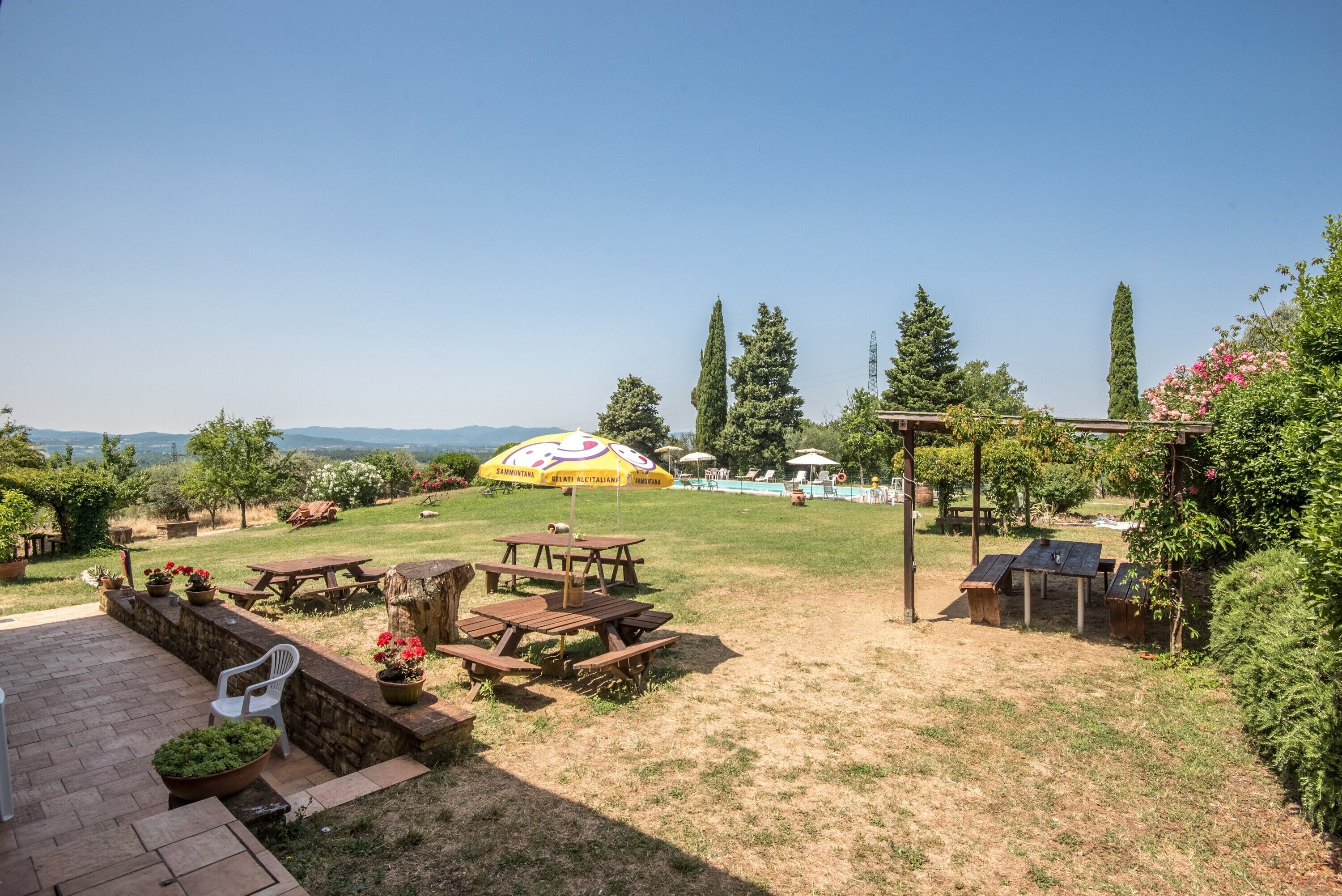 Un patio con mesas de picnic, un pérgola y vistas al campo.