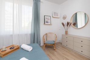 A neatly arranged bedroom with a bed, a chair, a dresser, and a mirror.
