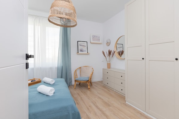 A bedroom with a bed, a chair, a dresser, and a wardrobe.