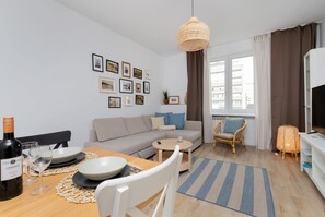 A modern living room with a sofa, dining table, and a hanging light fixture.