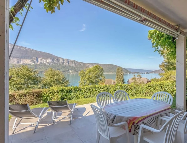 A patio with a table and chairs, overlooking a lake and mountains. - T3 Apartment – Résidence Bellevue (Talloires-Montmin)
