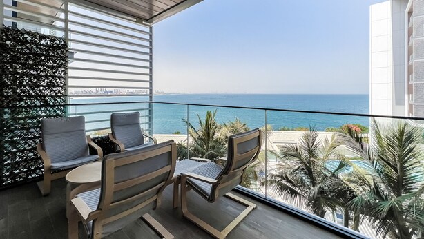 A balcony with a view of the sea, two chairs, a table, and a decorative wall. - Bluewaters Residences Building 5 Dubai (Dubai)