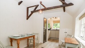 A compact kitchen with a dining area, wooden beams on the ceiling, and a view to the outside. - 7 Church Lane (Lymington)