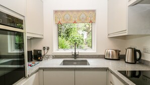 A modern kitchen with a built-in oven, a kettle, and a toaster on the countertop. - 7 Church Lane (Lymington)