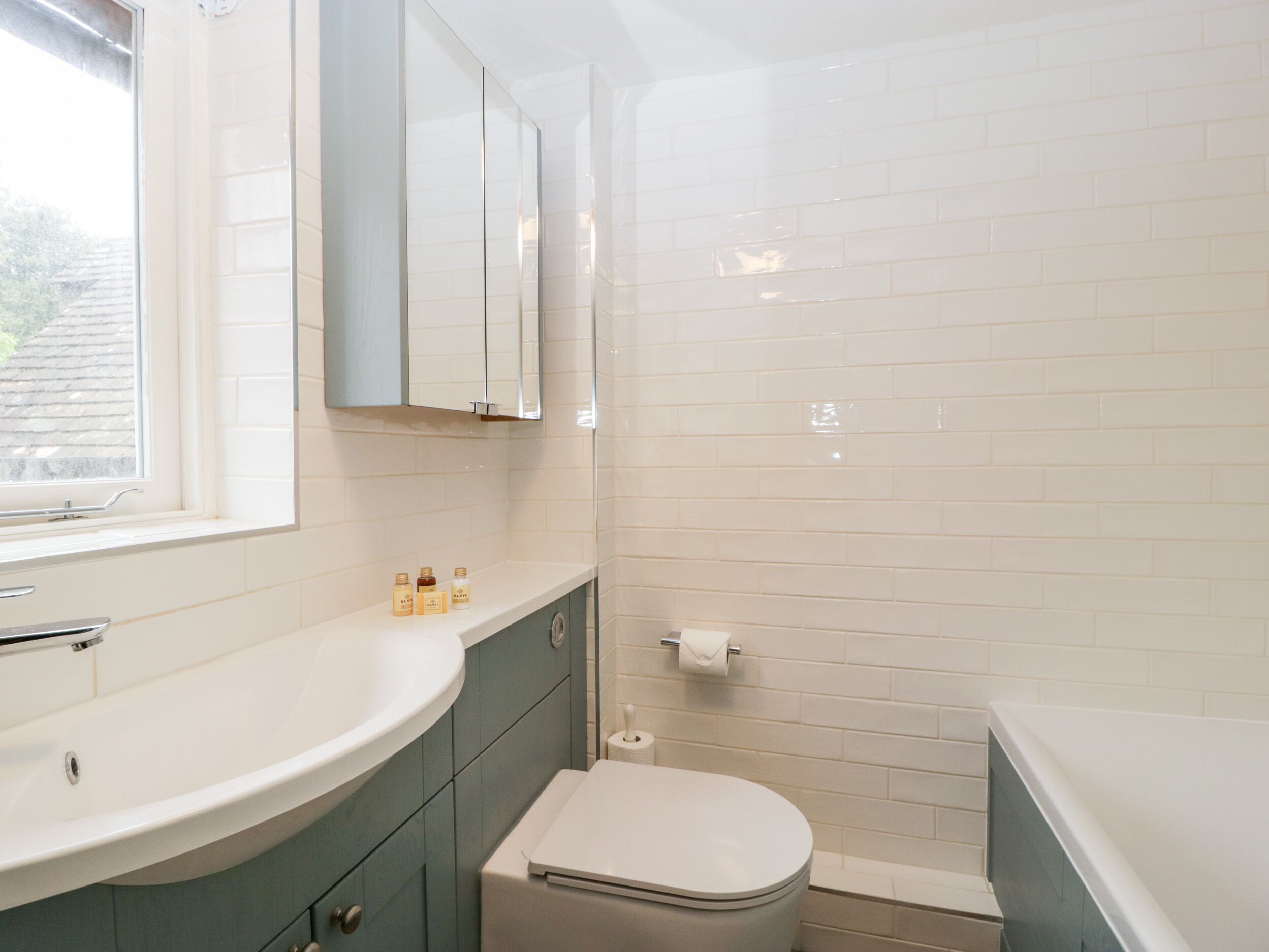 A bathroom with a white sink, a mirror, a toilet, and a shower area.