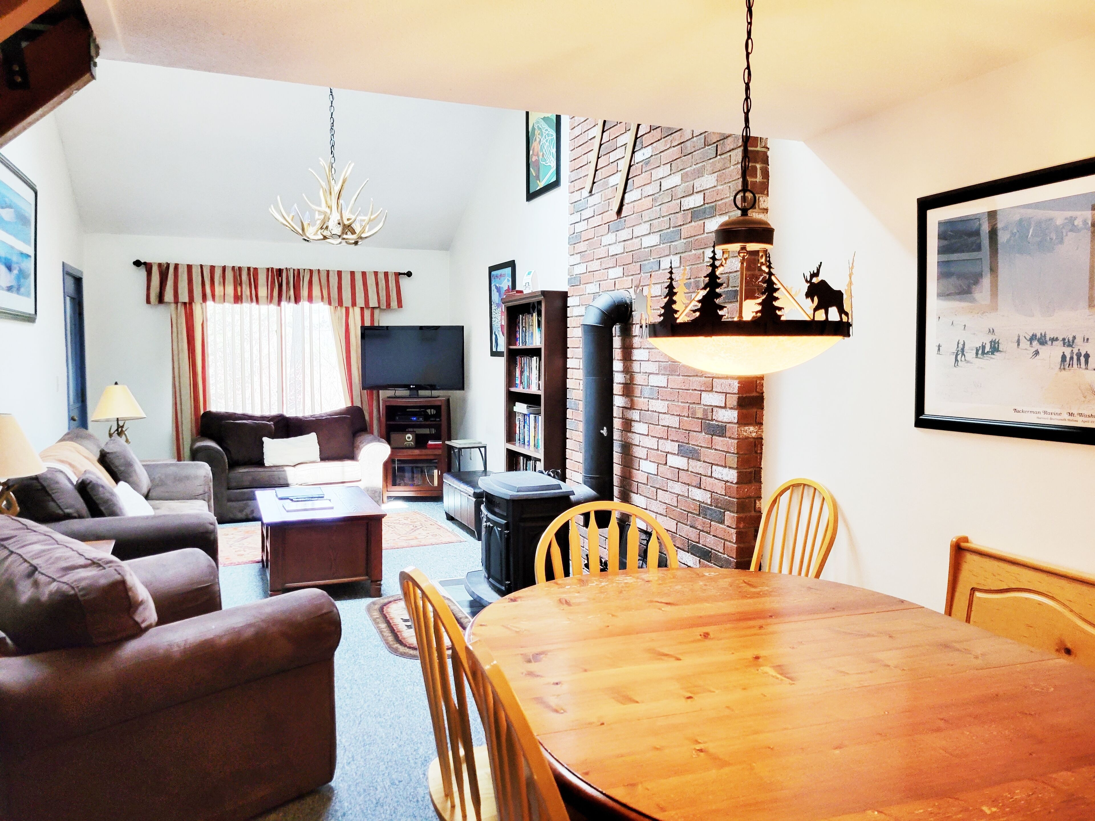 A living room with a sofa, a TV, a fireplace, and a dining table with chairs.