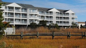 A multi-story hotel with balconies and a flat roof. - Cozy, comfortable 2 bedroom bayside condo with WiFi, an outdoor pool, and a breathtaking view of the bay located midtown and just a few blocks from the beach! (Ocean City)