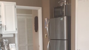 Une cuisine dotée d’un plan de travail en granit, d’appareils électroménagers en acier inoxydable et d’un luminaire suspendu.