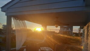 Une terrasse en bois agrémentée d’une pergola, de mobilier d’extérieur et offrant une vue sur le coucher de soleil.