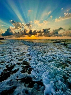 Uma praia com ondas e um pôr do sol.