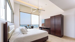 Ein modernes Schlafzimmer mit einem großen Bett, einem Deckenventilator, Meerblick und einem großen Kleiderschrank.