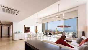 Ein modernes Wohnzimmer mit großem Fenster, einem Essbereich und einer Küche.