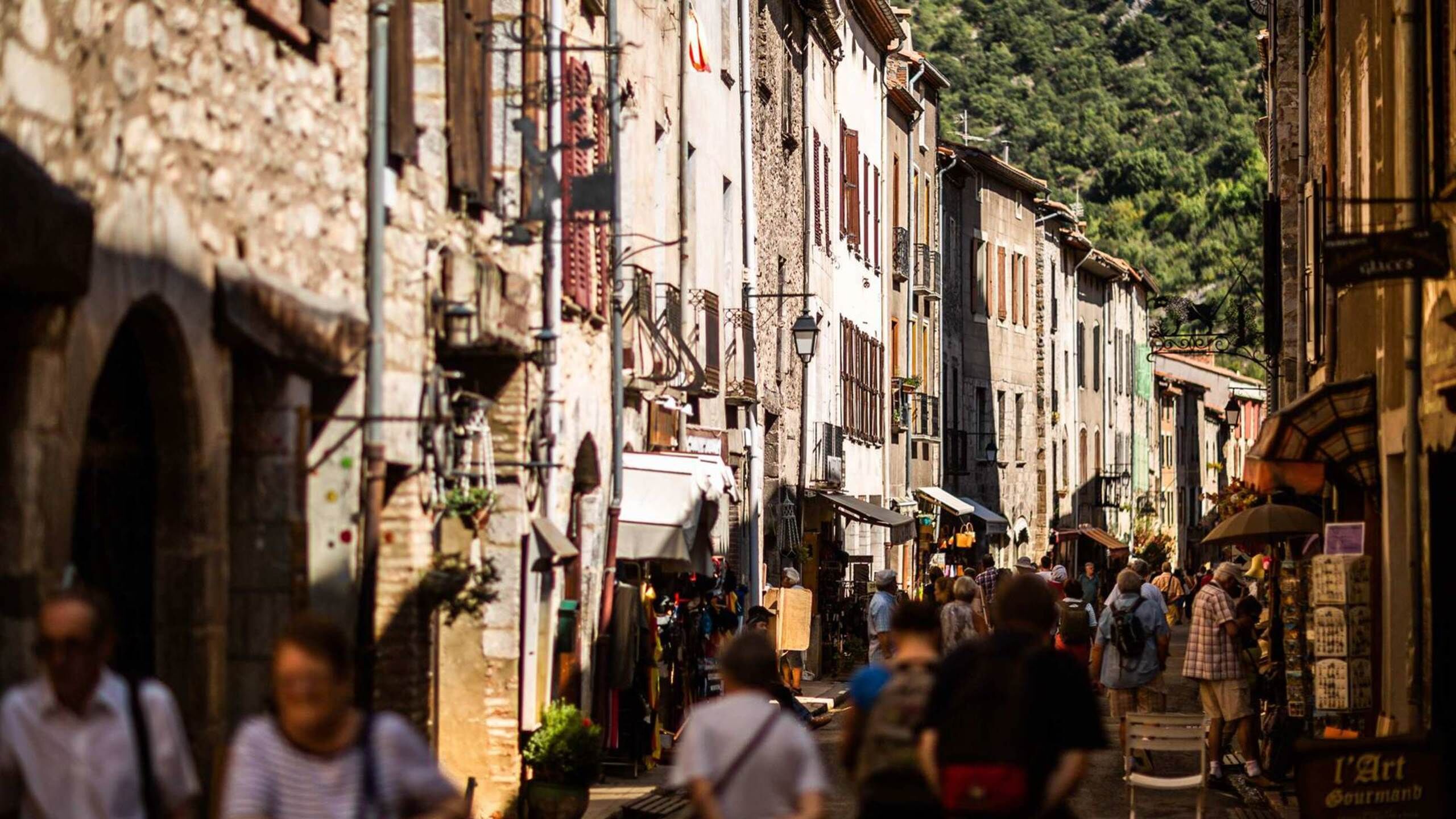 A bustling street scene with narrow, historic buildings, shops, and pedestrians.