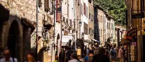 A bustling street scene with narrow, historic buildings, shops, and pedestrians.