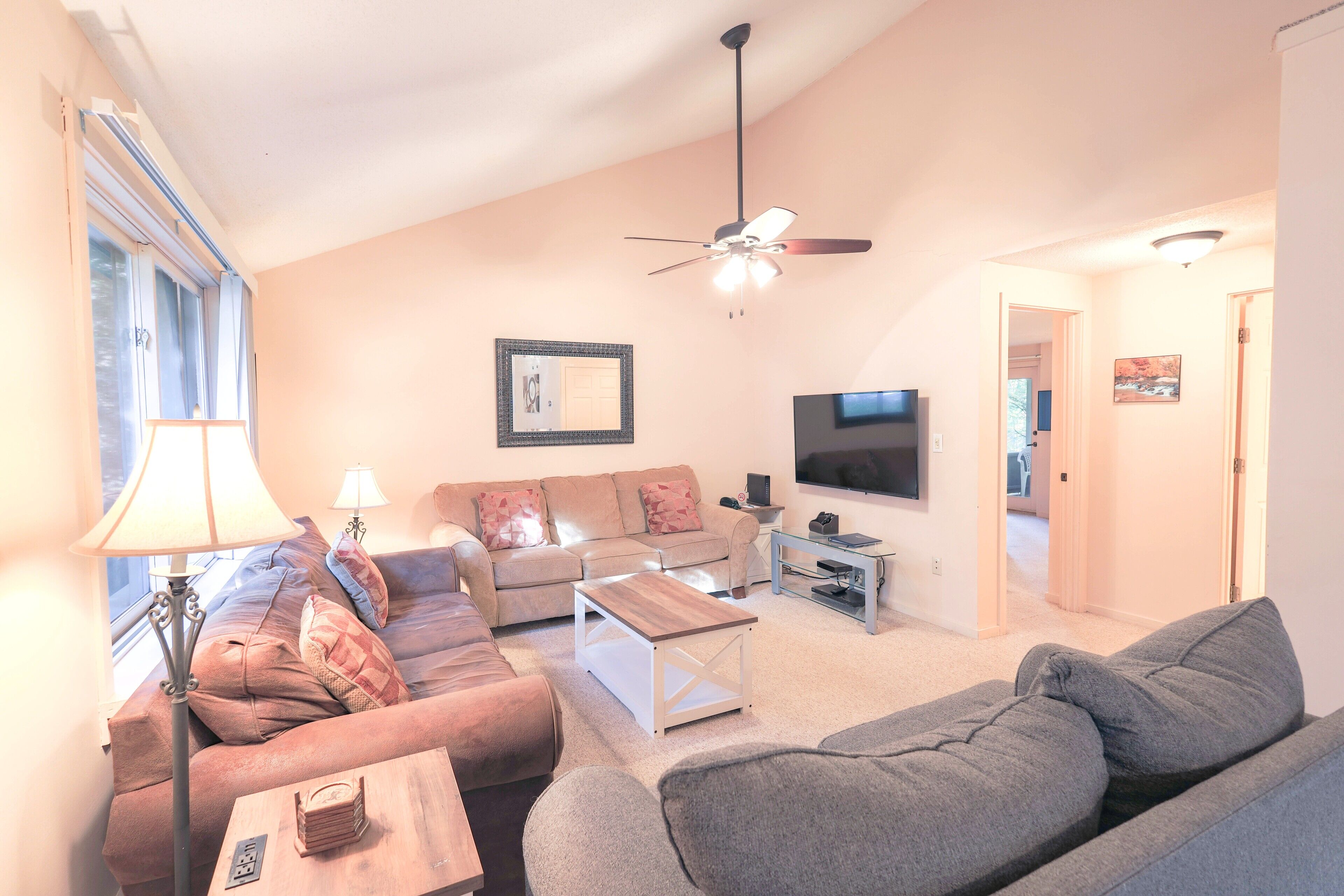 A living room with a sofa, a coffee table, a TV, and a ceiling fan.