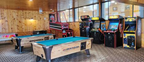 A recreational area with pool tables and arcade machines.