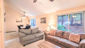 A living room with two couches, a coffee table, a ceiling fan, and artwork on the walls.