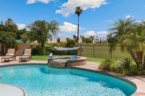 A swimming pool with lounge chairs and a hot tub, surrounded by palm trees and a grassy area. - Palm Springs Pool and Golf Oasis - Stunning Views & Private Pool in Palm Springs (Palm Springs)
