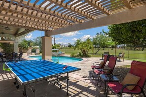 An outdoor pool area with a ping pong table, lounge chairs, and a pergola structure. - Palm Springs Pool and Golf Oasis - Stunning Views & Private Pool in Palm Springs (Palm Springs)