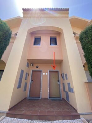Um edifício com duas portas, uma pequena janela e entrada com azulejos.