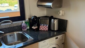 A compact kitchen with a built-in washing machine, a coffee maker, and a toaster.