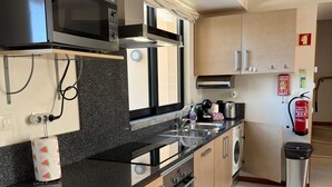 A modern kitchen with a microwave, stove, sink, and cabinets.