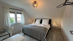 Makuuhuone, jossa on sänky, yöpöydät, työpöytä ja ikkuna, jossa on verhot.