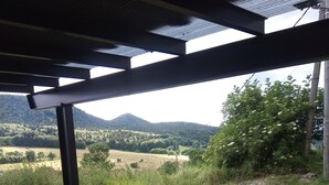 An outdoor seating area with metal tables and chairs, overlooking a rural landscape with fields and hills. - Audrey and Etienne's (Présailles)