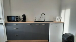 A compact kitchen with a microwave, coffee maker, sink, and dishwasher. - Audrey and Etienne's (Présailles)