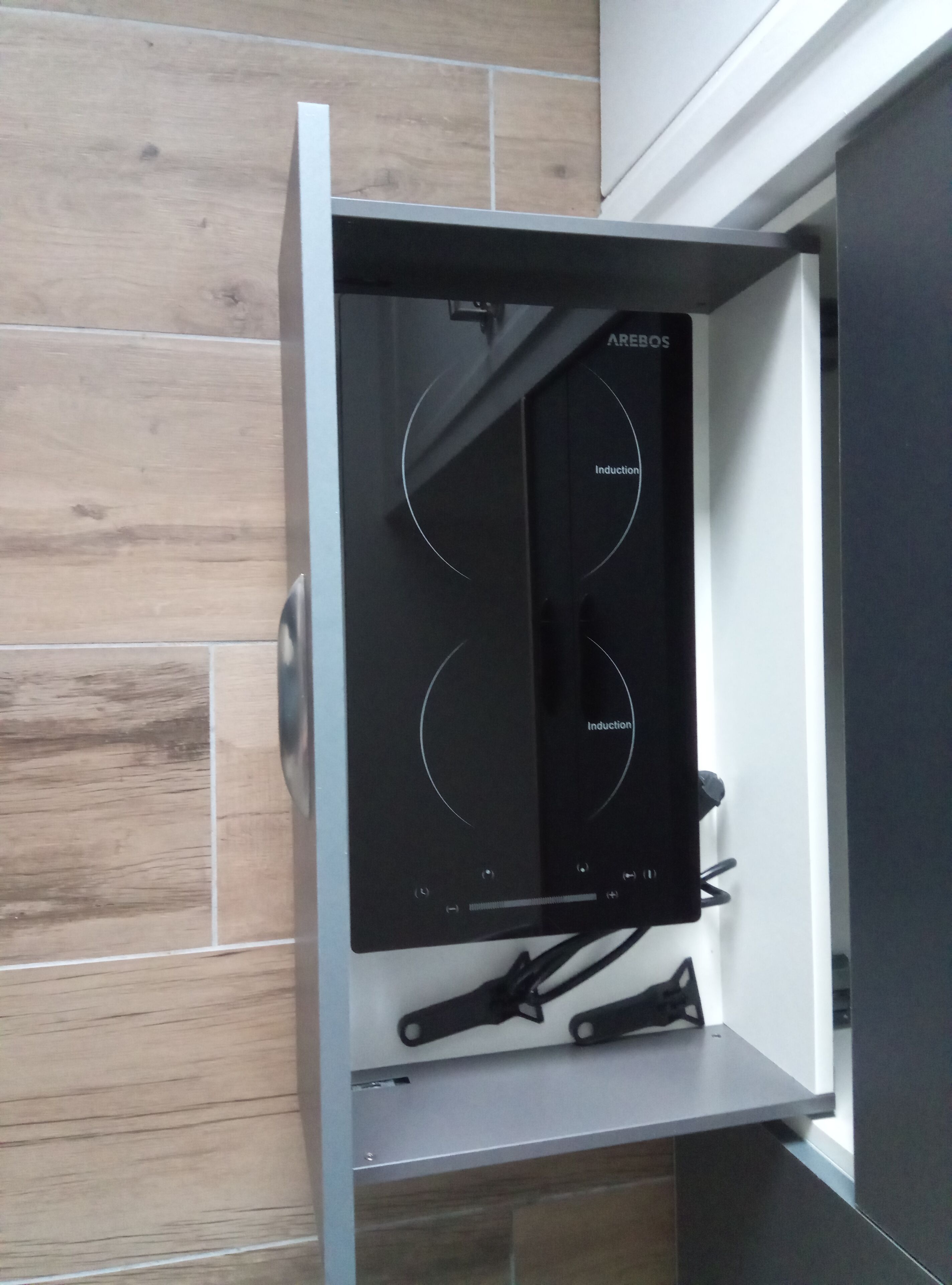 Eine Küche mit einem Bosch-Induktionskochfeld, einer Holzspritzschutzwand und einem modernen, minimalistischen Design.