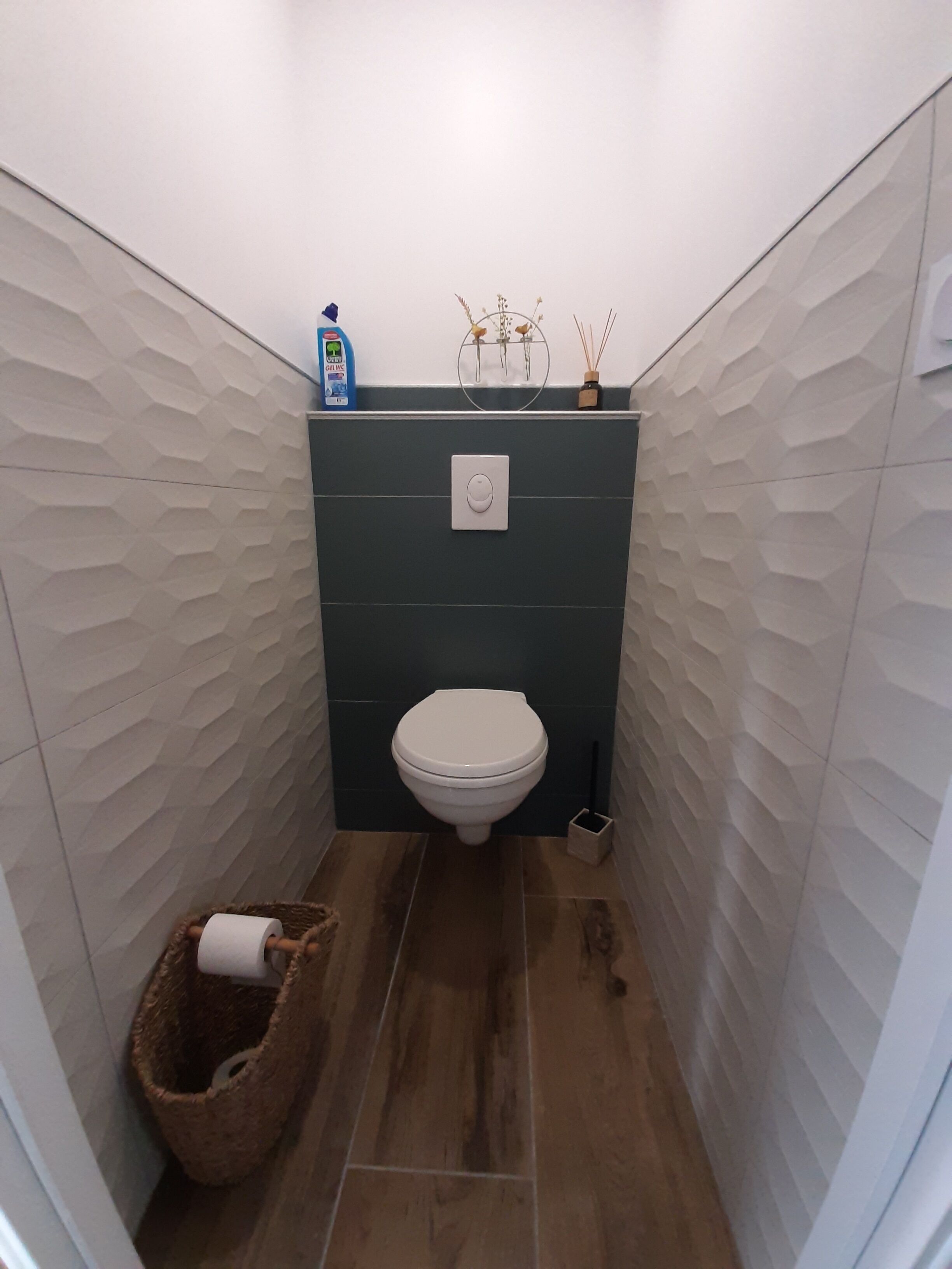 Une petite salle de bain comprenant des toilettes, une poubelle et un distributeur de savon fixé au mur.