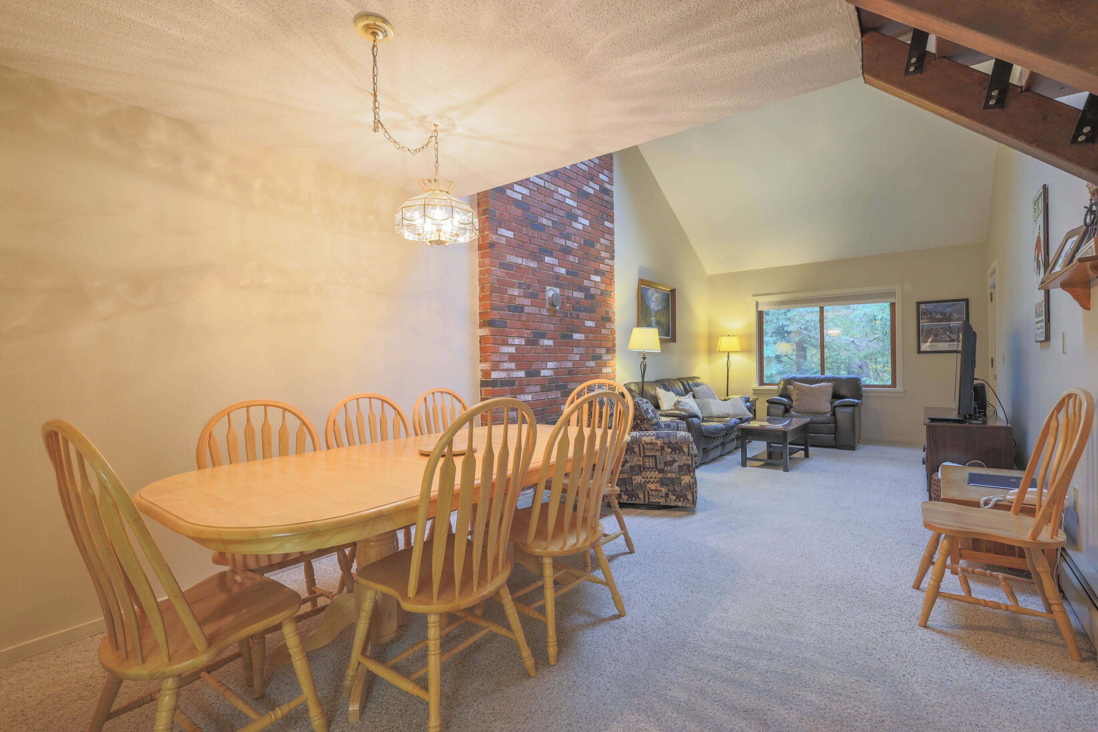 A dining area with a brick wall, wooden chairs, and a chandelier.