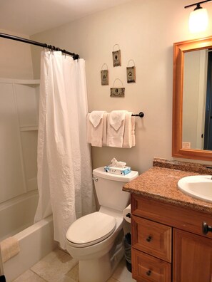 Een bad/douchecombinatie, een haardroger, handdoeken