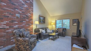 A living room with a brick wall, a sofa, a coffee table, and a television.