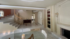 A spacious living area with a marble staircase, a fireplace, and a dining table with chairs. - Panorama Hills Villa (Pylaia-Chortiatis)