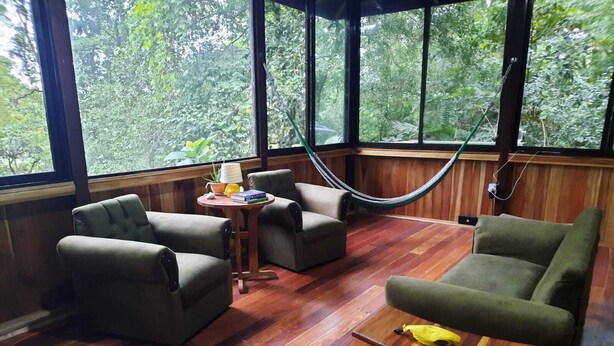 Una habitación con suelo de madera, una hamaca y dos sofás.