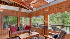 L’intérieur d’un chalet en bois comprend un canapé, des fauteuils, une table et de grandes fenêtres donnant sur un lac.
