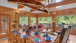 Une cabane en bois dotée d’un coin repas, de grandes fenêtres et offrant une vue sur l’extérieur.
