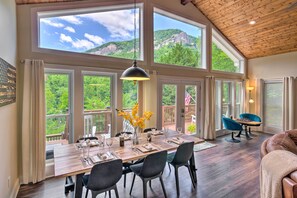 Enjoy a meal with a panoramic view of the mountains from this dining area with a large wooden table and comfortable seating.