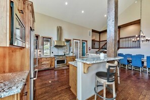 Une cuisine spacieuse avec des meubles de rangement en bois, un îlot central et un coin repas doté de chaises bleues.