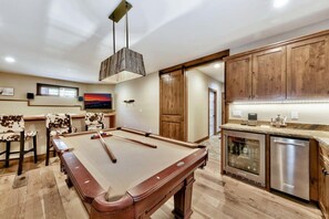 A pool table in a room with wooden cabinets and a kitchen area. - Make Memories Together in This Spacious 5BR Tahoe Retreat - Enjoy Built-In Midweek Savings! (South Lake Tahoe)