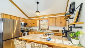 A kitchen with wooden cabinets, a stainless steel refrigerator, a large island with seating, and a hanging light fixture. - Boone Hideaway w/ Deck, Grill & Hot Tub! (Boone)