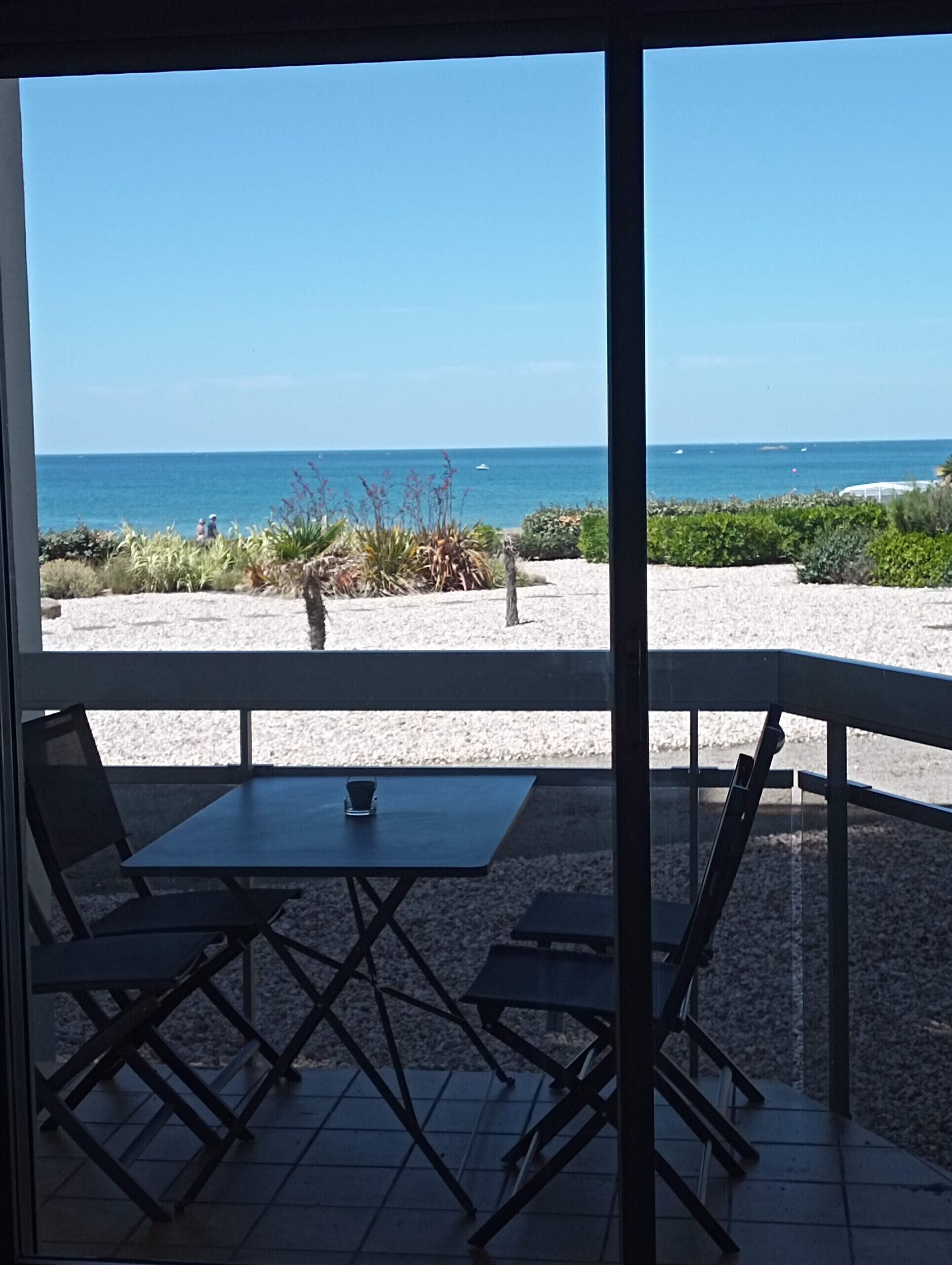 A patio with a table and chairs overlooking a beach.